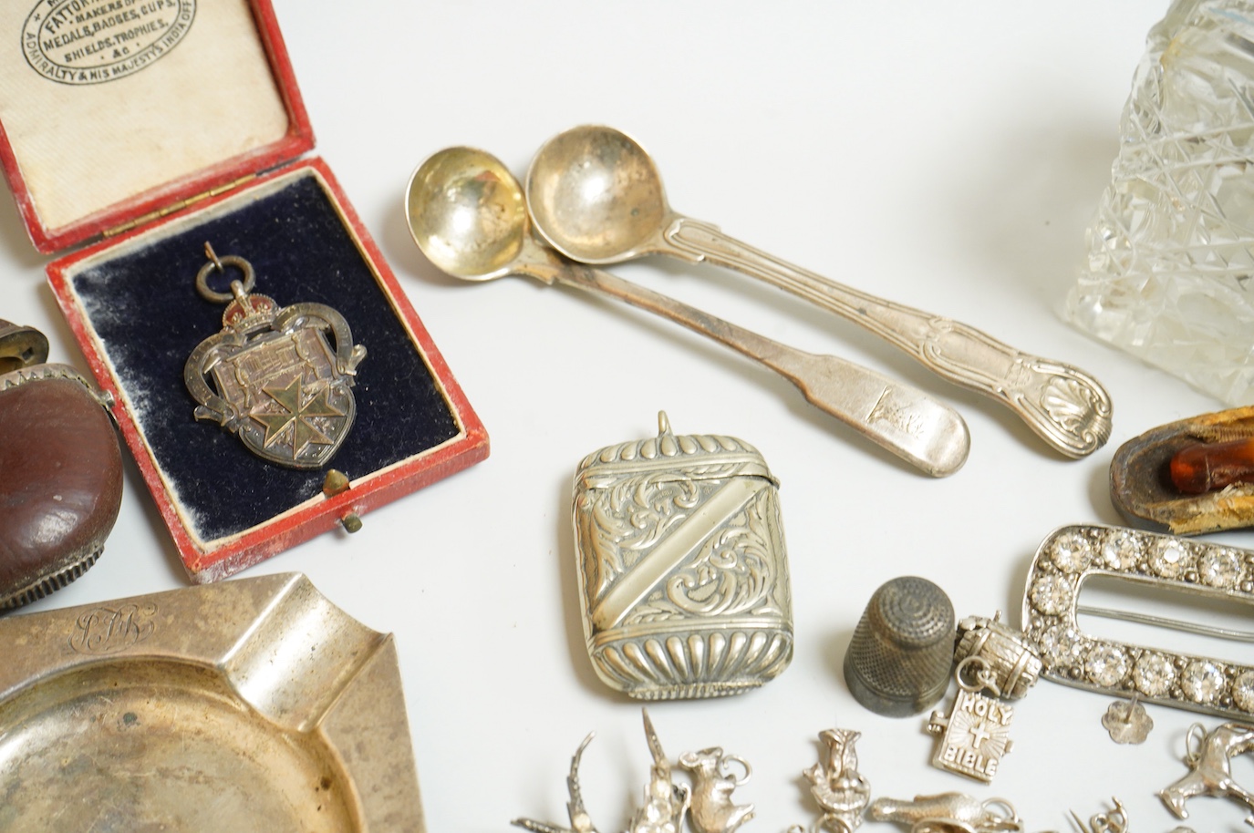 A small collection of silver and white metal charms, including Holy Bible, Penny Farthing, hedgehog and squirrel, together with a silver compact and ashtray, a silver and paste brooch, nut vesta, pipe, etc.